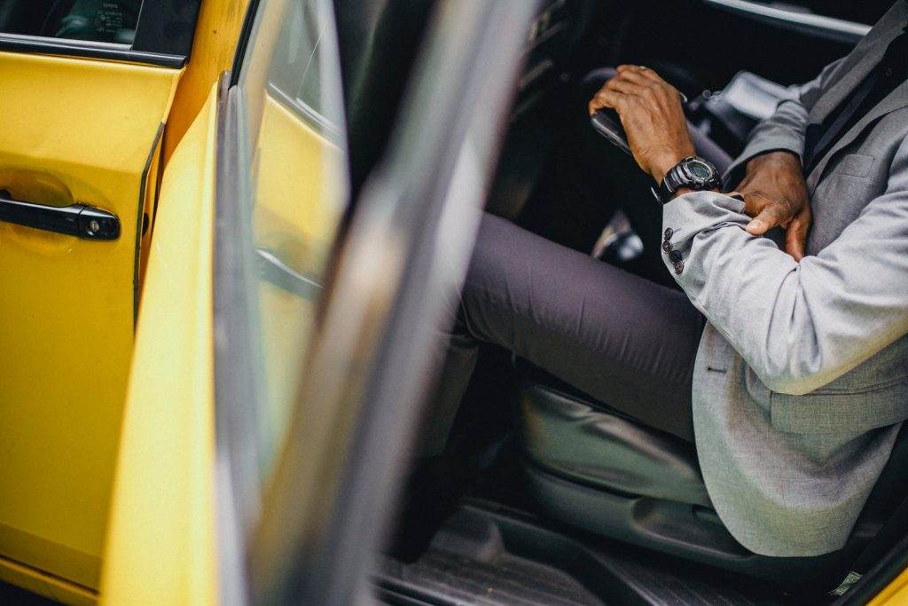 Side view of crop anonymous African American male in elegant suit checking wristwatch in car