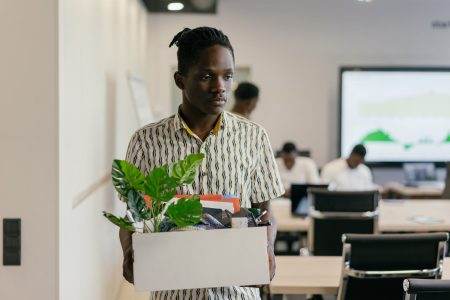 Sad Man in Button Down Polo Carrying White Box with Green Plant and Things in it