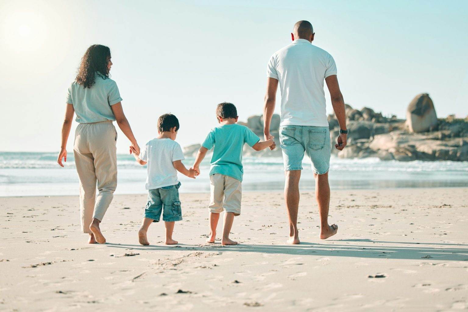 Beach, holding hands and rear view of family walking at the sea, fun and travel on blue sky backgro