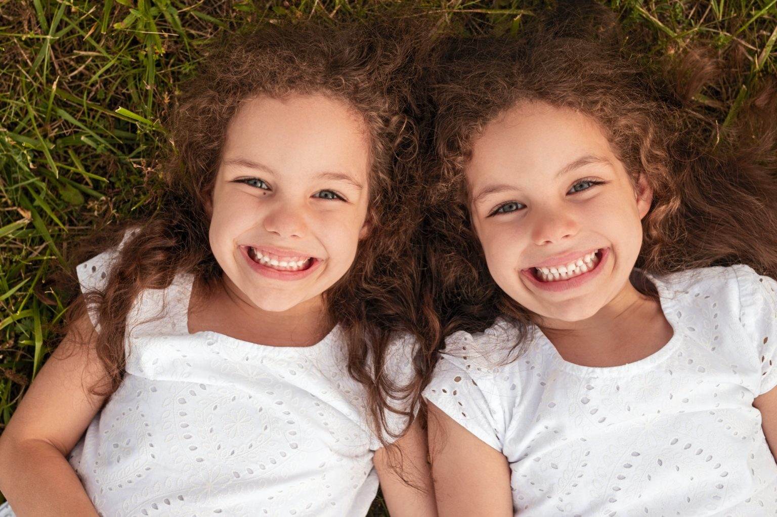 Cheerful twins lying on grass