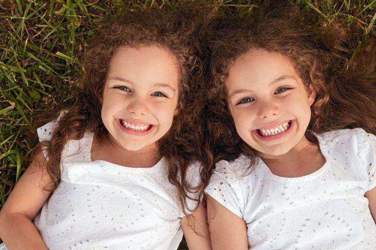 Cheerful twins lying on grass