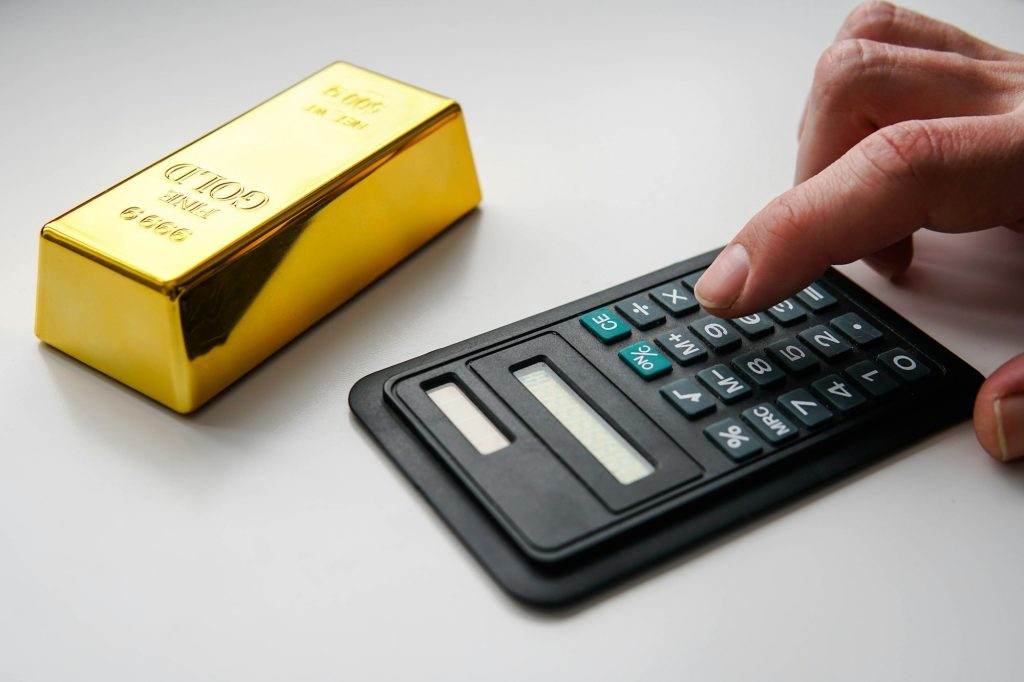 Man using calculator for buying a gold bar. Buying gold bars for investment.