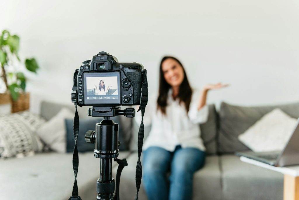 Selective focus photo of woman sitting on sofa, making video for social media