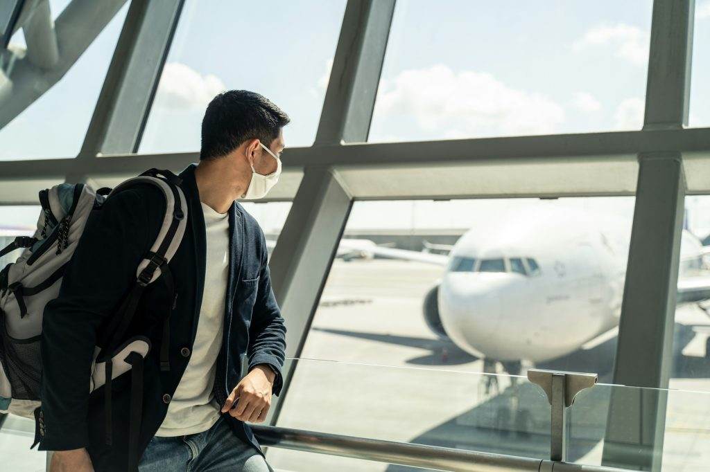 Asian traveler business man wait to board into airplane, standing in departure terminal in airport