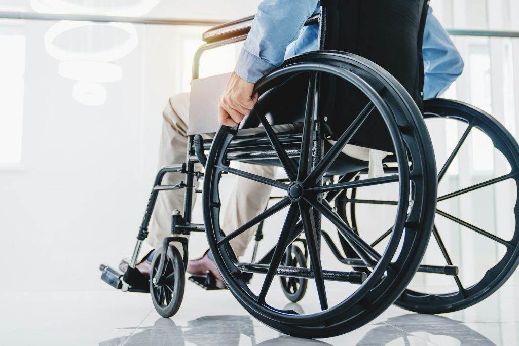 Cropped of senior handicapped man sitting in wheelchair taken care of in hospital