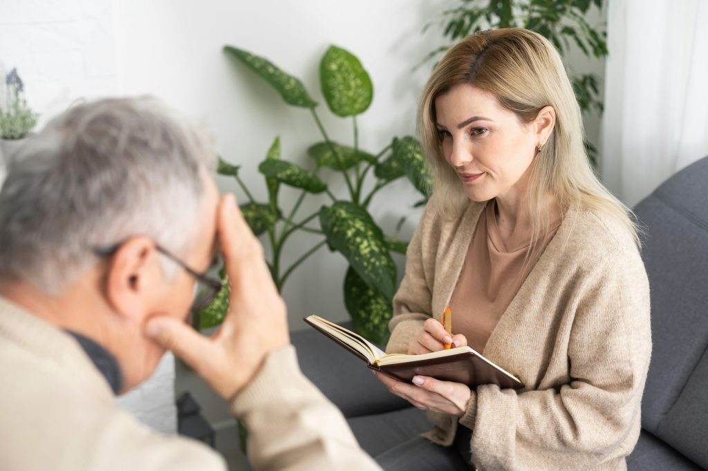 Mature man at a session with a psychologist. The doctor listens and writes. Help with depression