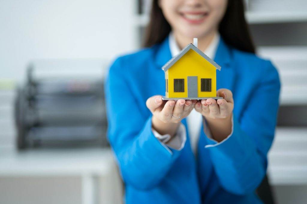 Real estate house agent showing house model to customer, real estate housing concept.