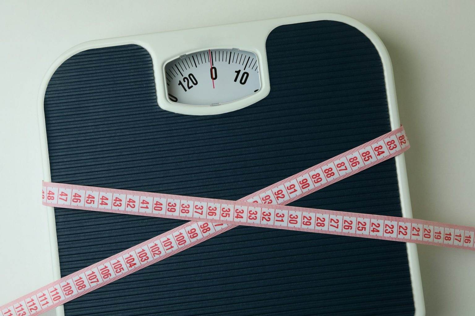 Scales with measuring tape on white background