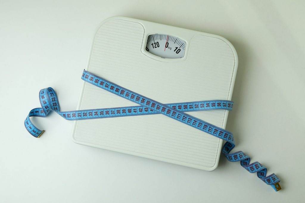 Scales with measuring tape on white background