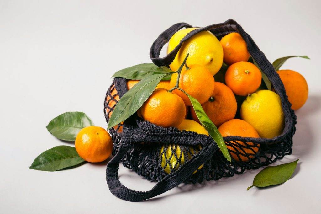 Tangerines and lemons in textile bag. Healthy food and zero waste concept