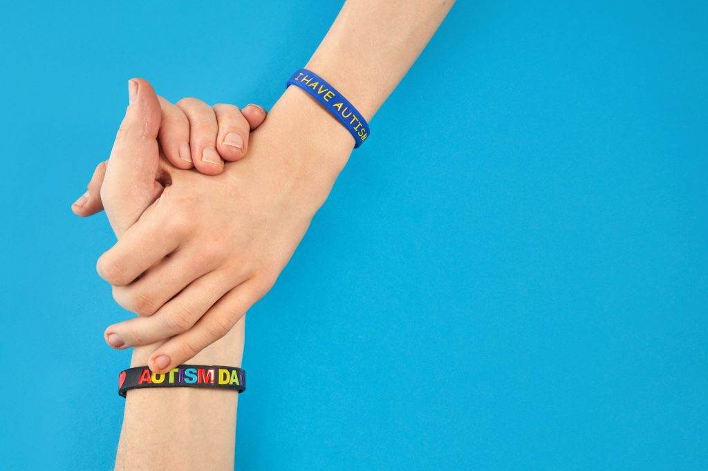 Autism Awareness. Autism father holding hand his Autistic Child with I have autism bracelet