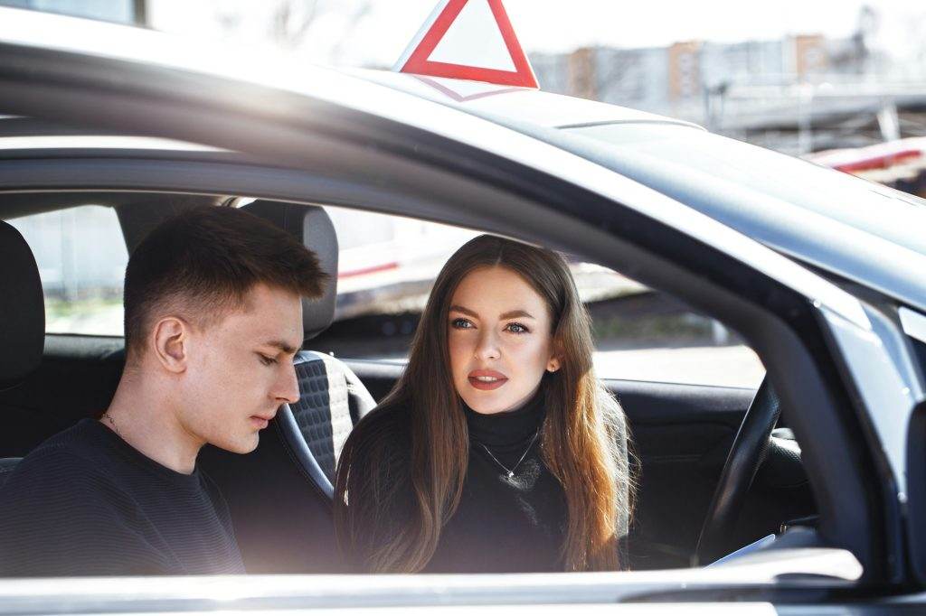 Driving instructor and woman student in examination car.