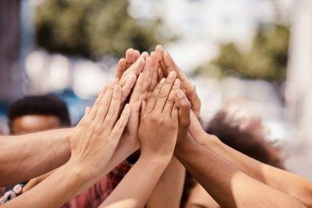 Hands, teamwork and solidarity with a group of people standing outdoor in the city in a huddle or c