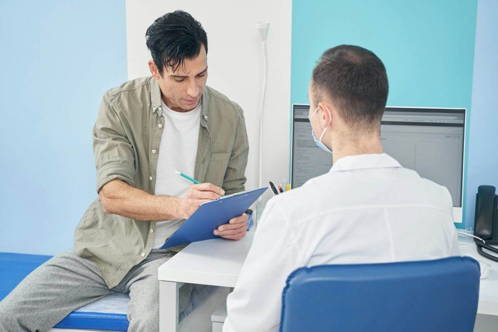 Patient describes his health, doctor looking at him