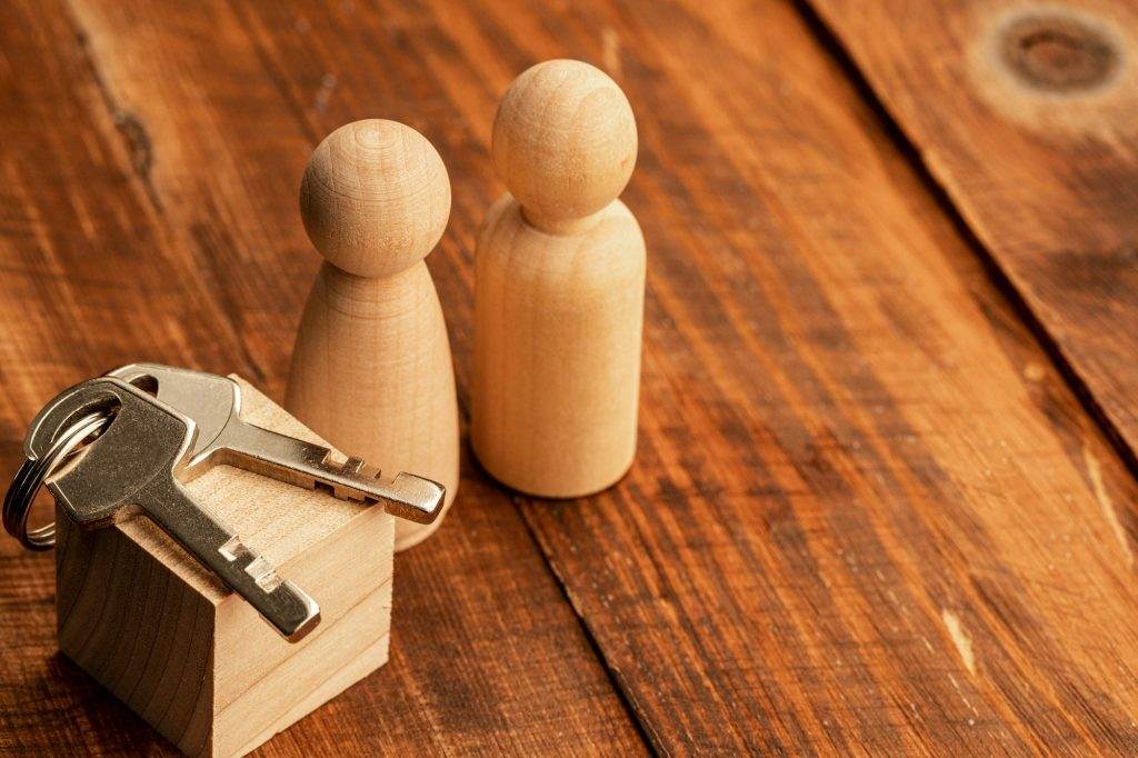 Real estate concept with toy wooden figures and house key
