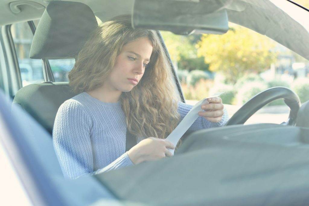 Unhappy woman reading penalty receipt in car