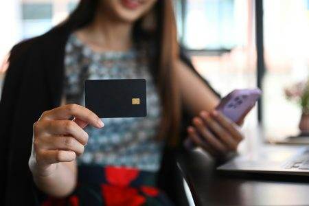 Young businesswoman holding black credit card. Banking, shopping online and e-commerce concept.