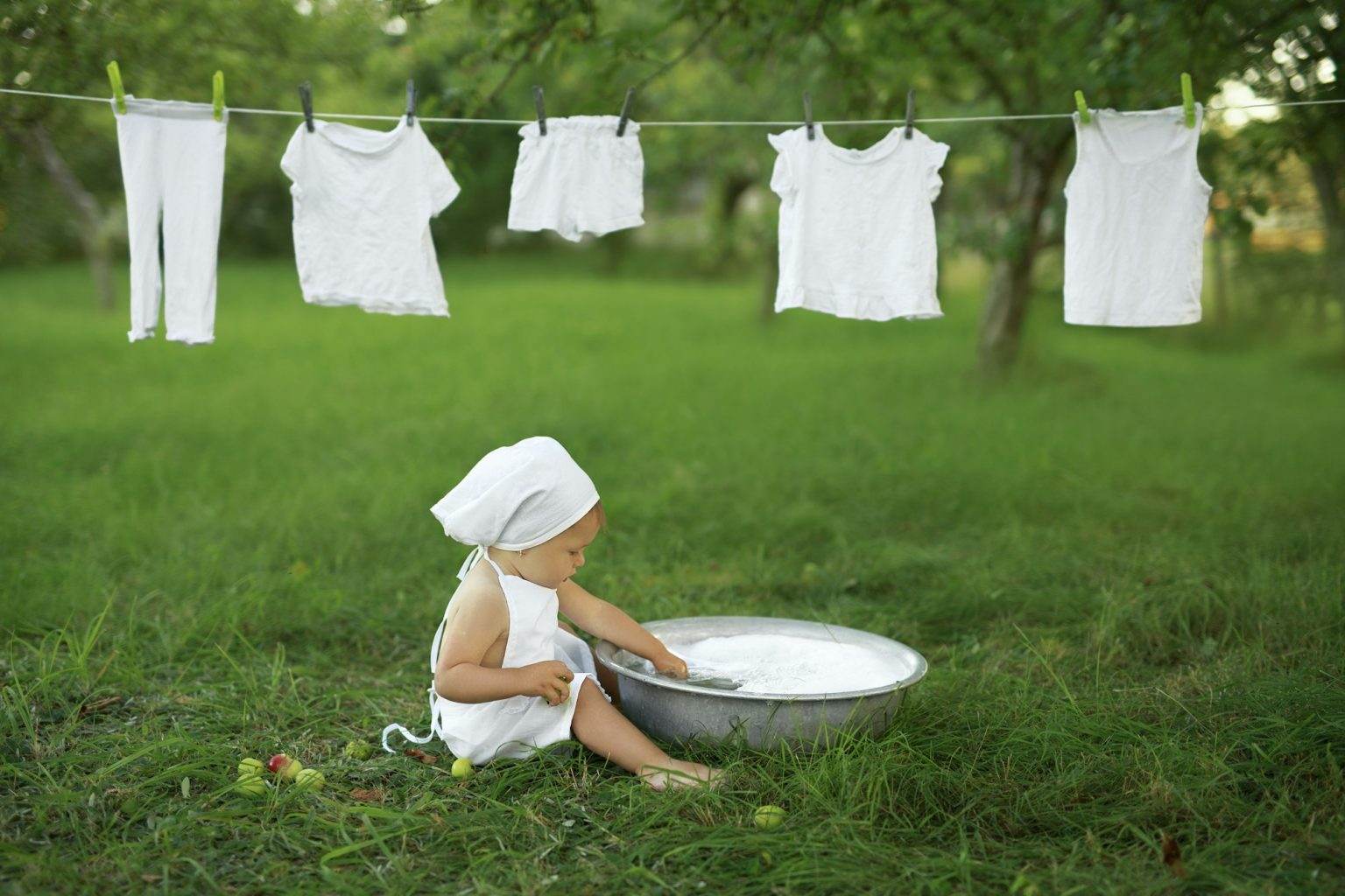 Comment blanchir efficacement son linge : les meilleures astuces Baby washes white clothes in the garden in nature.
