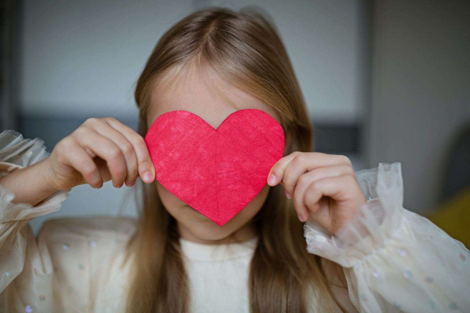 Little school kid girl with red heart. Valentine's day during pandemic coronavirus covid-19