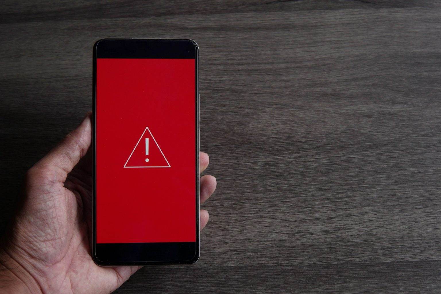 Smartphone with triangle caution warning icon.