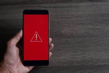 Smartphone with triangle caution warning icon.