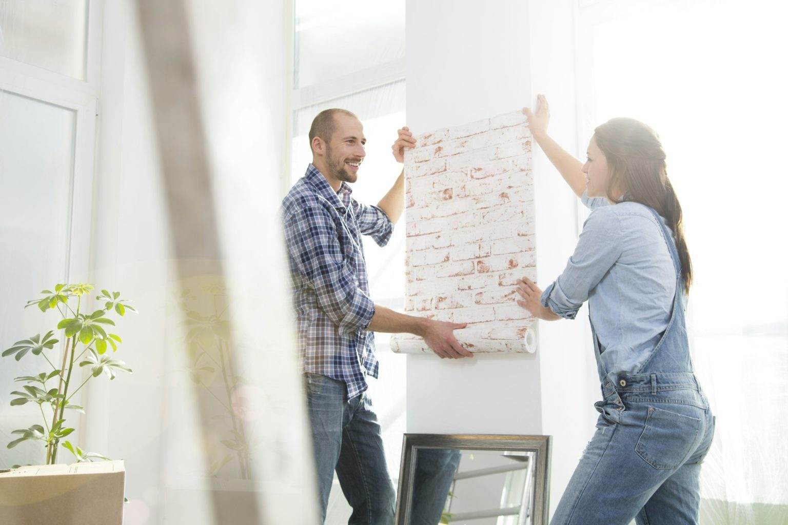 Young couple moving into new home, testing wallpaper