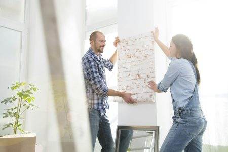 Young couple moving into new home, testing wallpaper