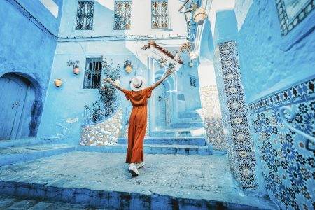 Young woman with red dress visiting the blue city Chefchaouen, Marocco