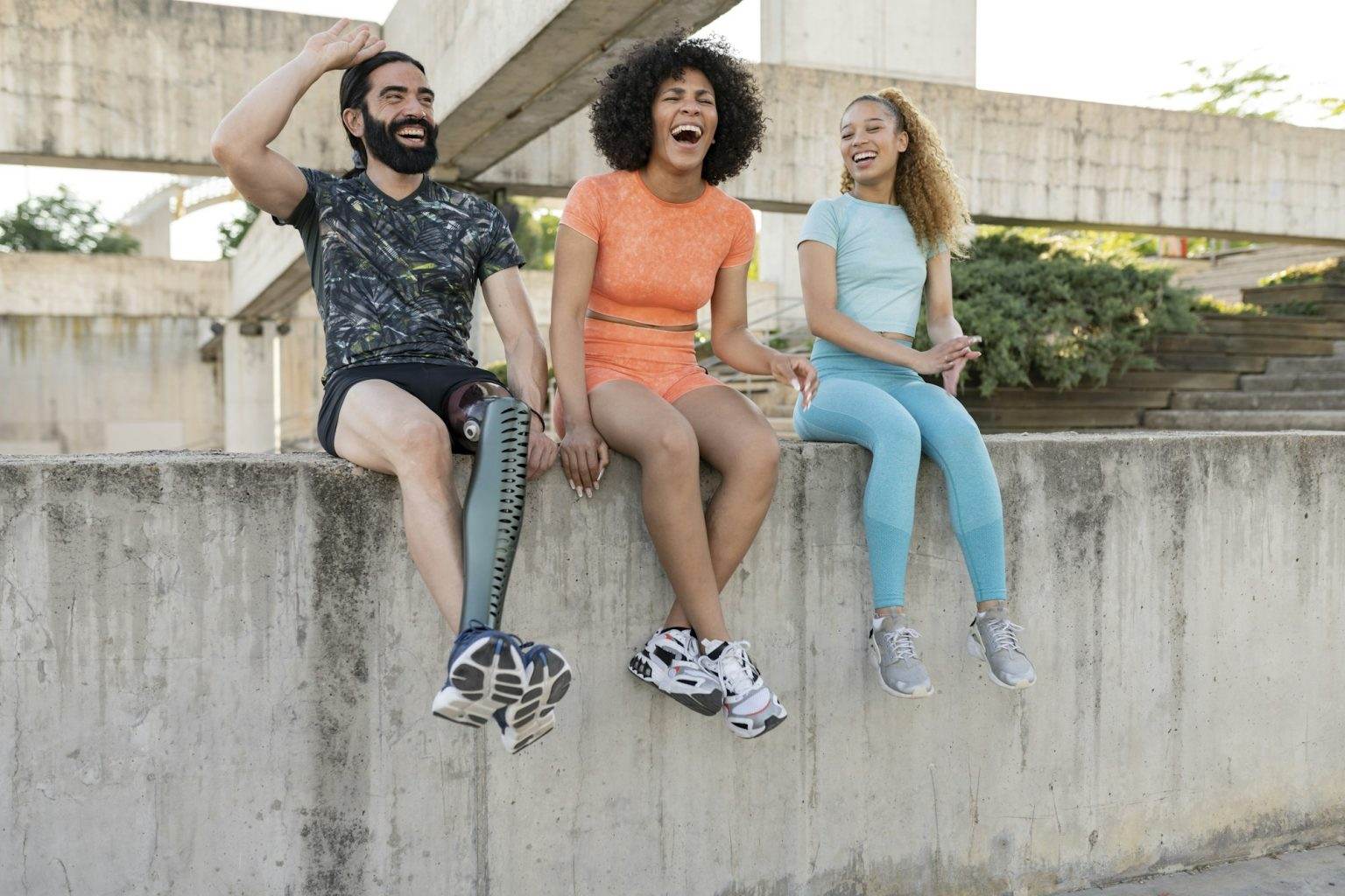 cheerful young athletes chatting outdoors, the man has an amputated leg and wears a prosthetic leg.