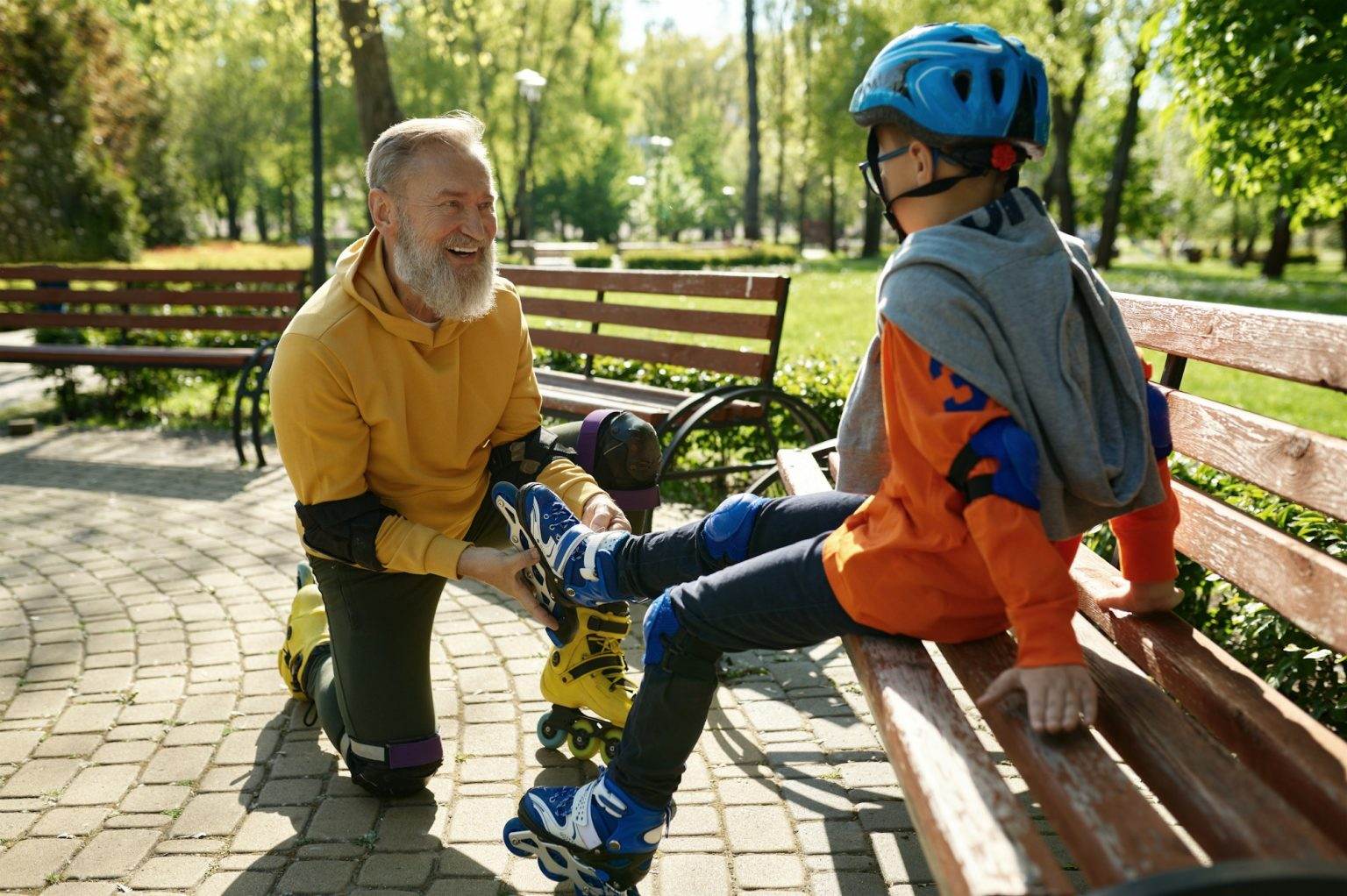 Father helping son to put on roller skates in urban park
