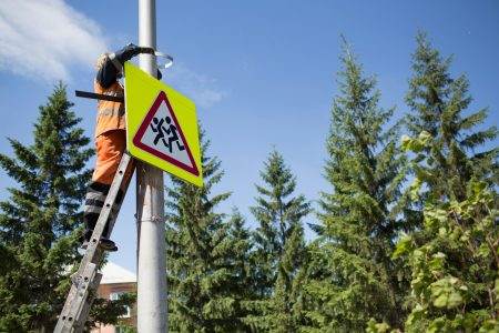 Installation road sign on pole. Road worker sets sign.