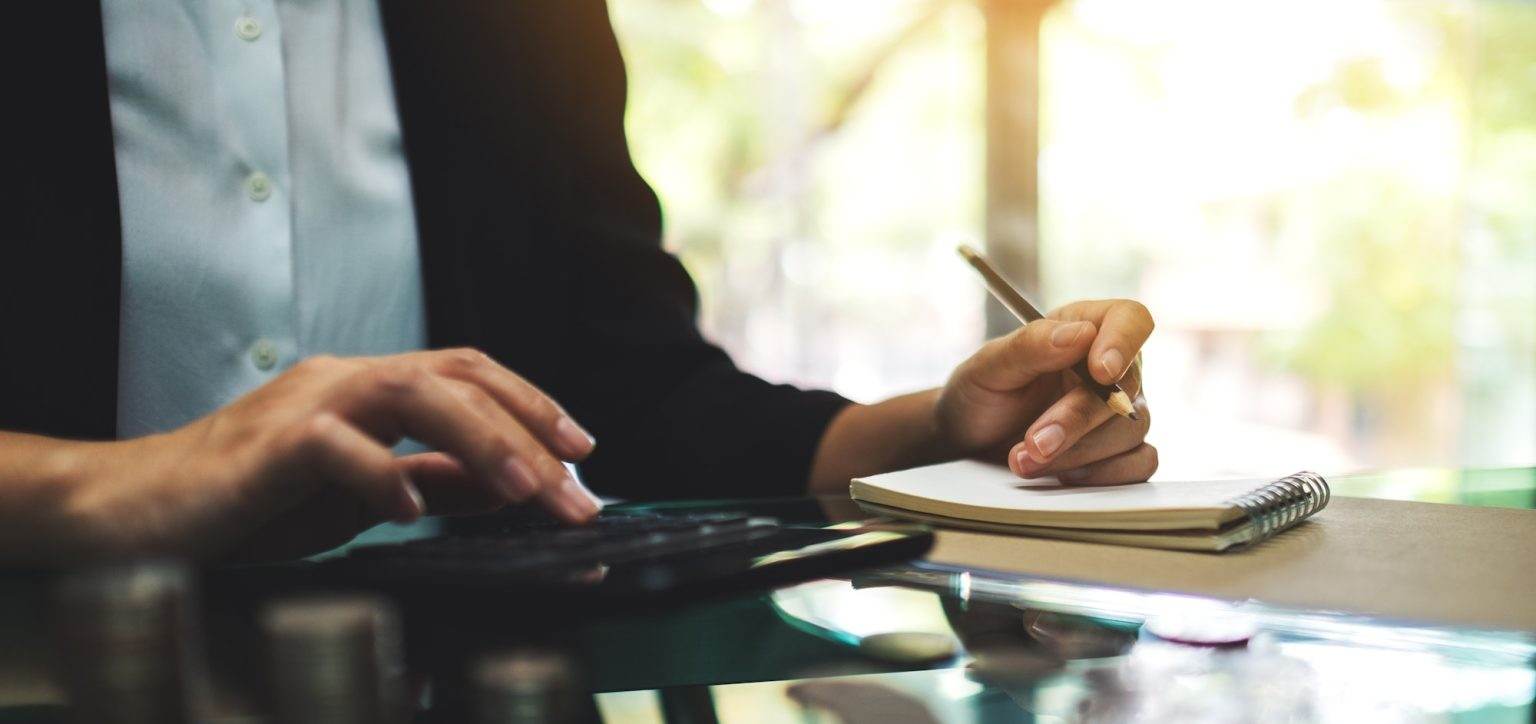 Closeup image of a business woman working , calculating and writing on notebook in office