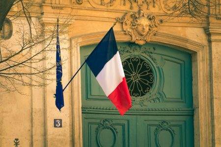 French flag hanging outside a beautifully ornate building