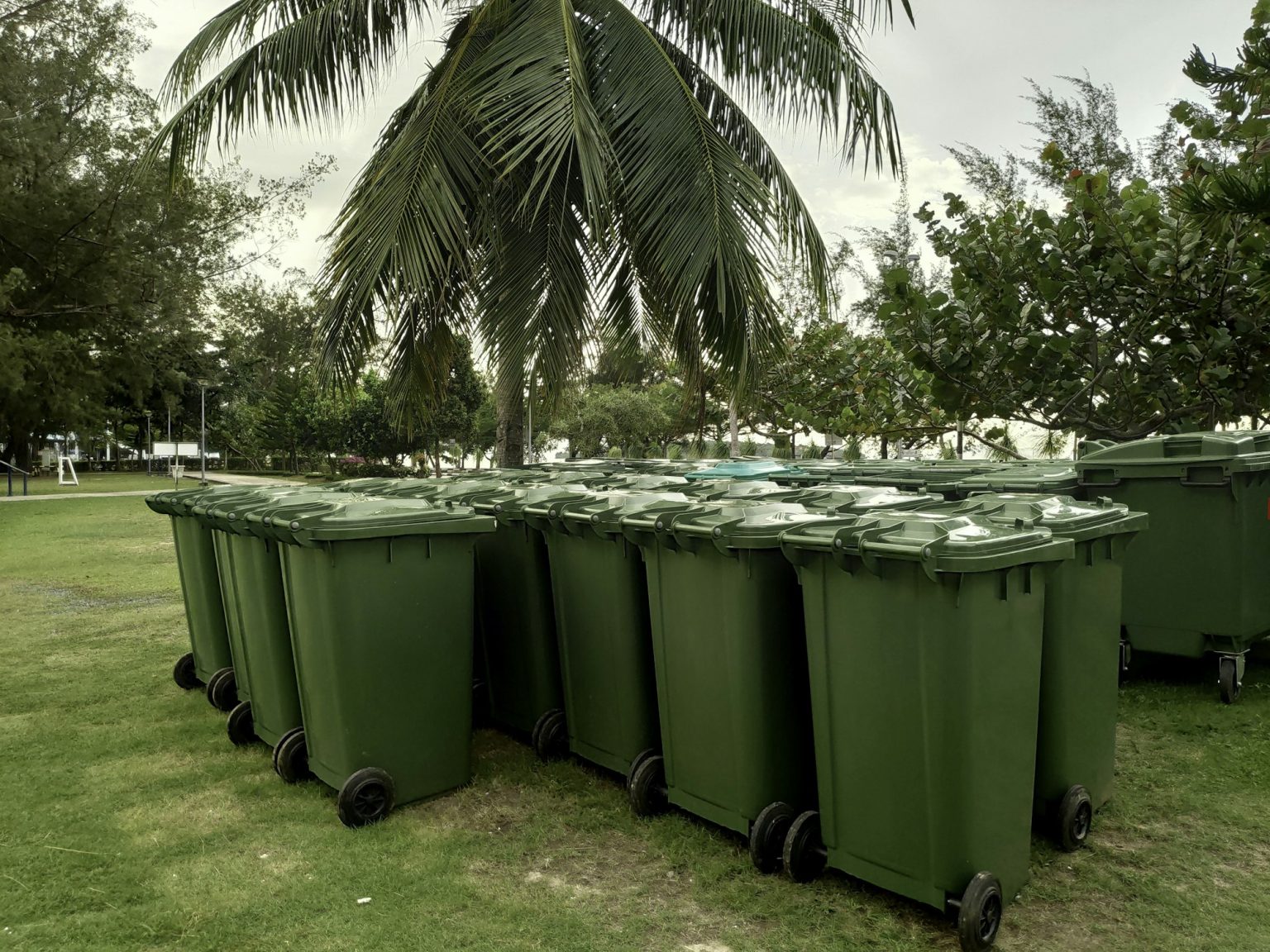 A row of green dustbin with sun flare.Pollution concept.