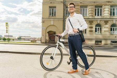 Le Marquage Obligatoire des Vélos : Comment ça Fonctionne ? A stylish man in a white shirt stands confidently with his bicycle in an urban setting, radiating