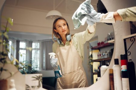 Cleaning, bathroom and mirror with a woman washing glass in a house for hygiene with disinfectant o