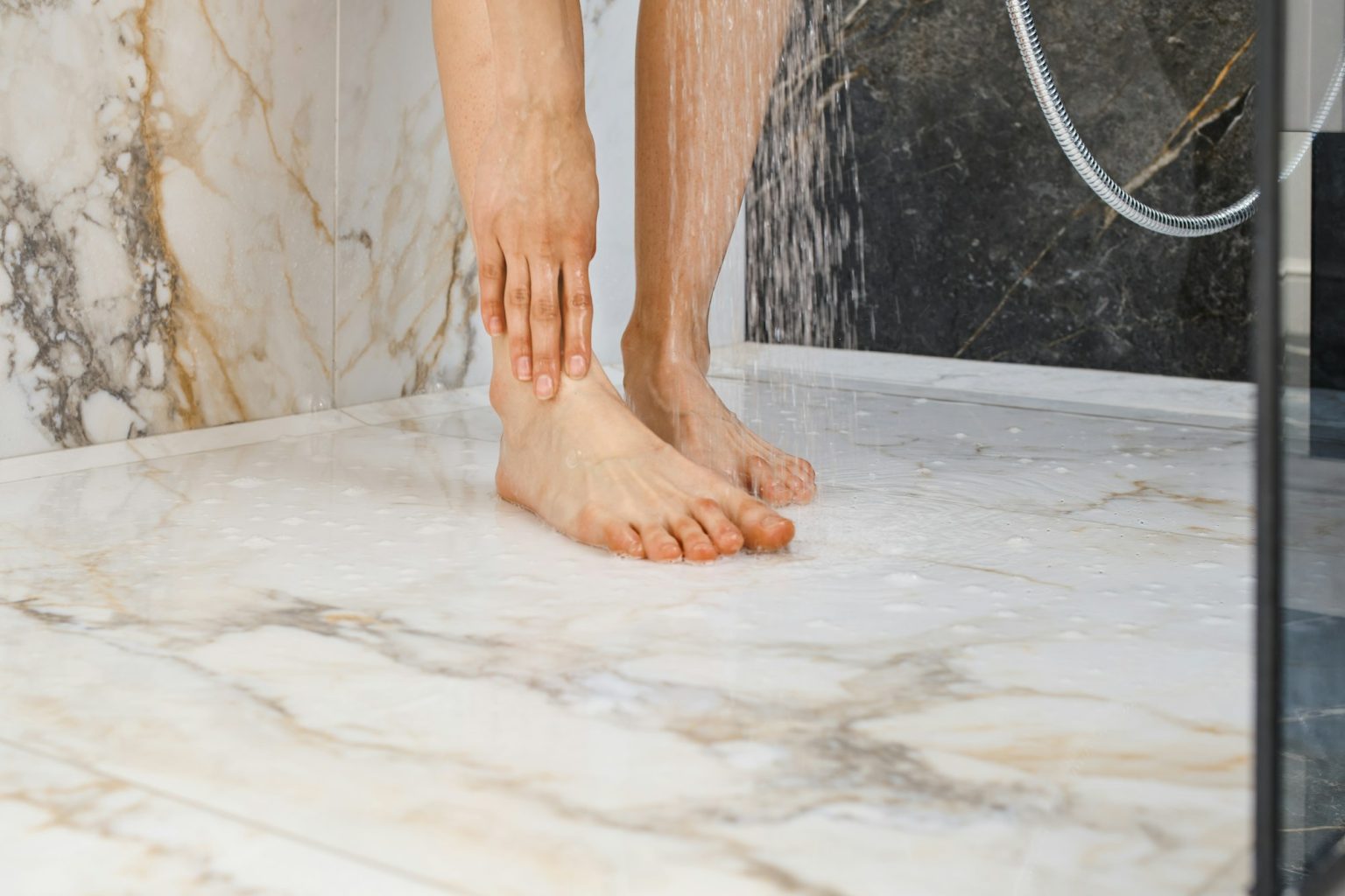 Closeup view of washing feet in shower cabin.