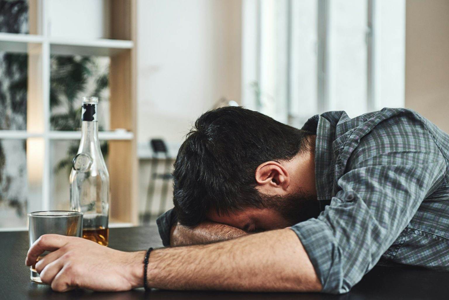 Drunkenness is temporary suicide. Alcohol abuse: drunk man lying down on a table with glass of