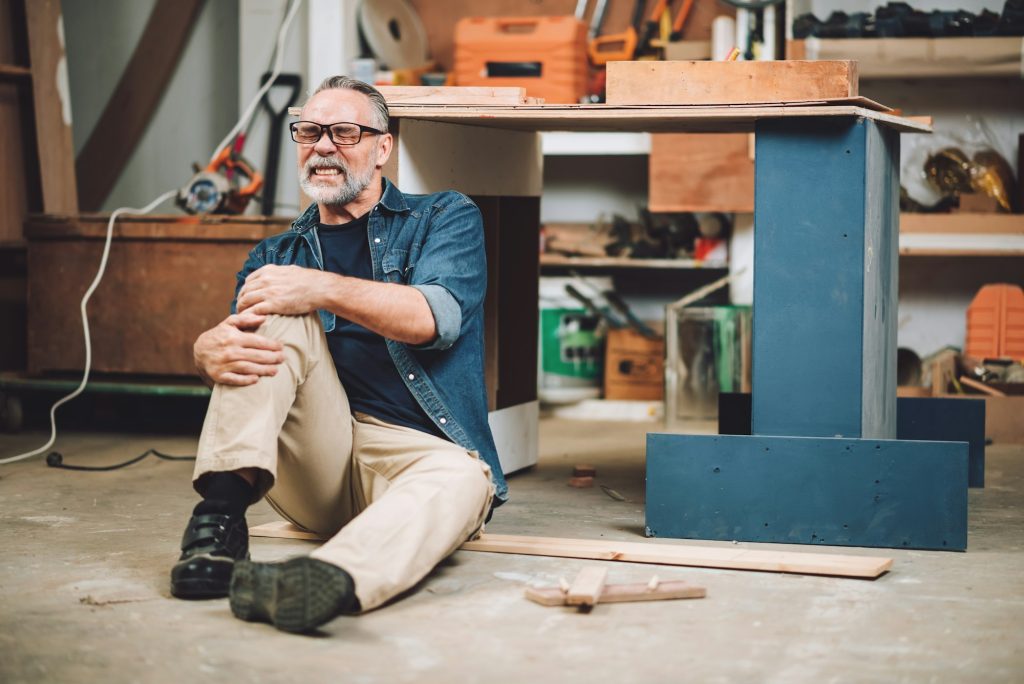 Senior caucasian man has an accident while working in wood workshop