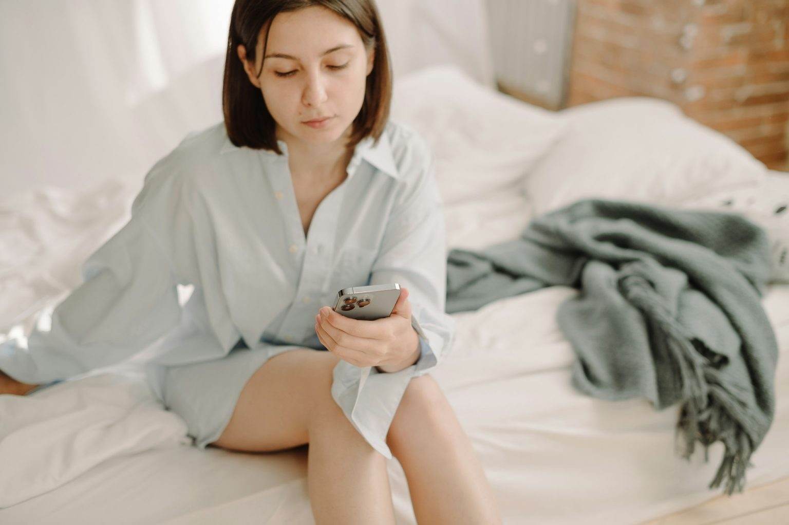 woman on bed using blue iphone 13pro, technologies, morning routine, working from home