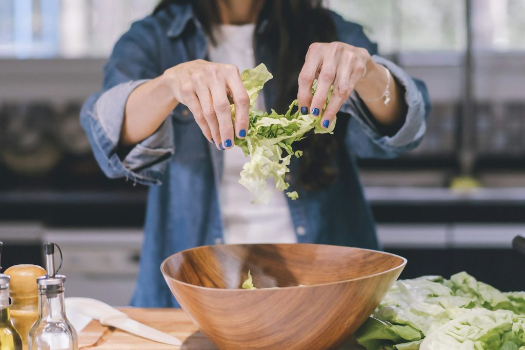 A woman preparing a green salad in her kitchen.