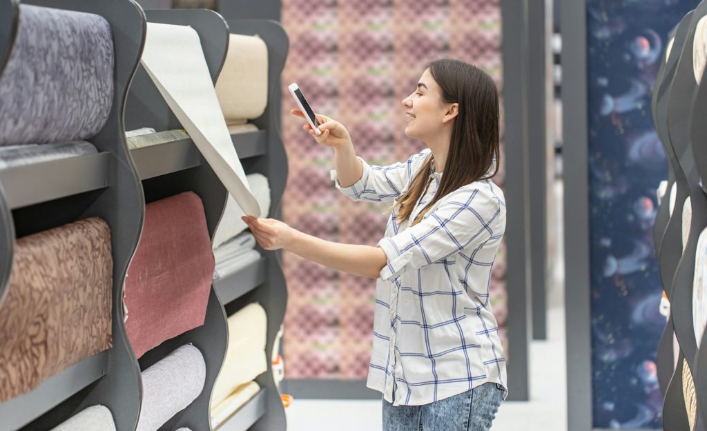 A young woman in a store chooses Wallpaper for her home.