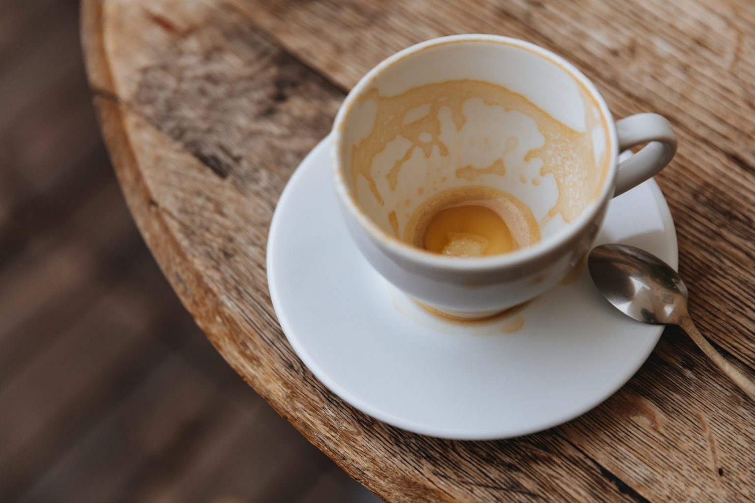Coffee stain in almost empty white cup on wooden table