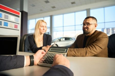 Dealer calculates the price of the car on a calculator