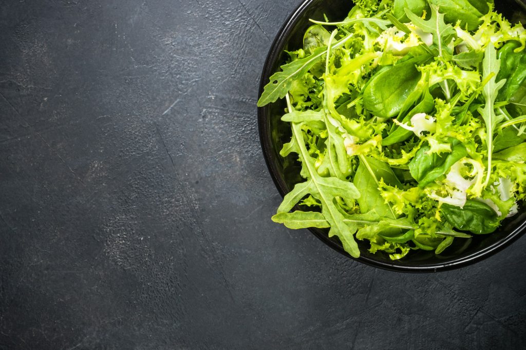 Green salad leaves mix on black top view
