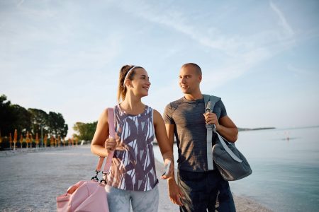 Happy couple of athletes walking on the beach.