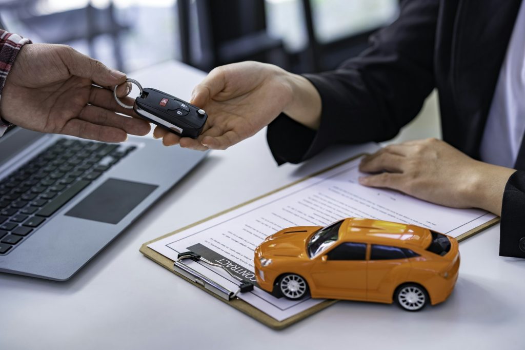 Insurance officers hand over the car keys after the tenant. have signed an auto insurance document o