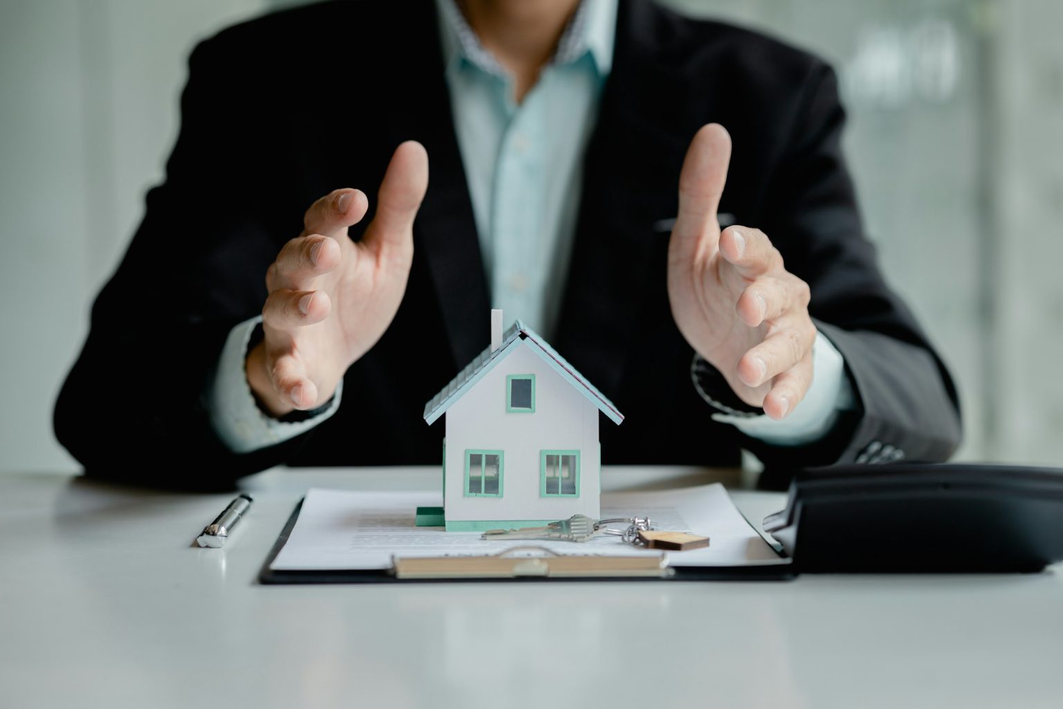 Comment souscrire une garantie décennale ? Person covers the model with his hand, Insurance house.
