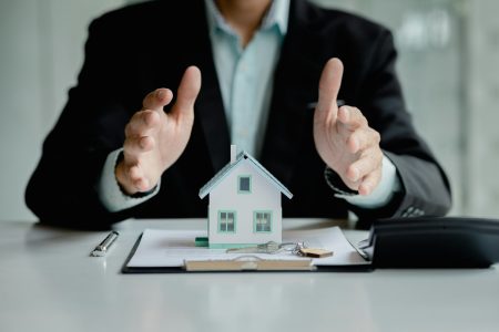 Person covers the model with his hand, Insurance house.