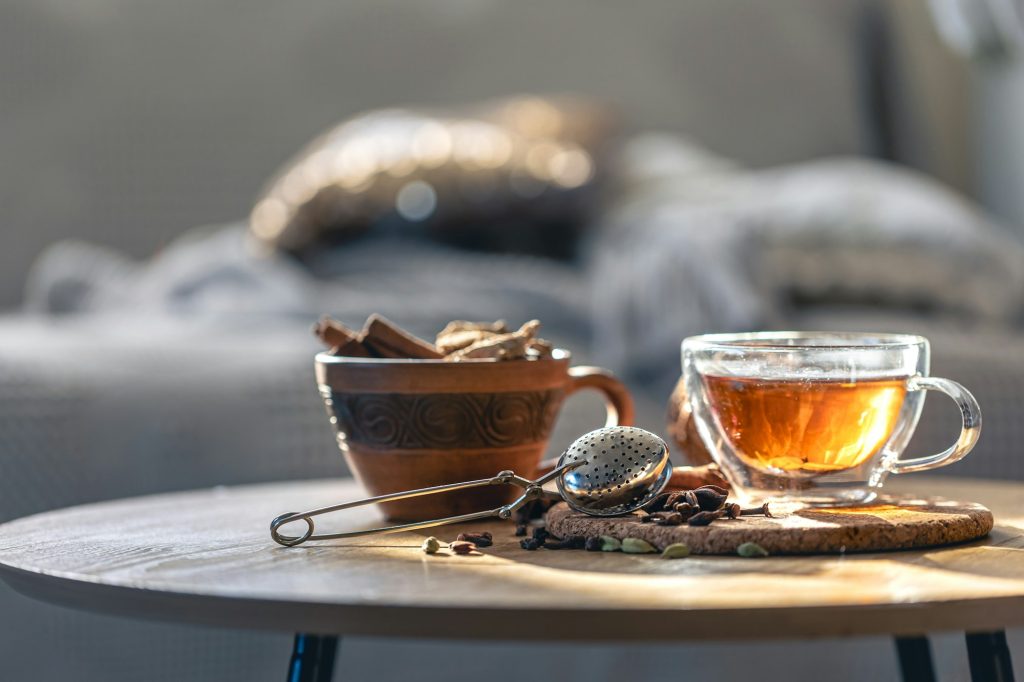 Tea ceremony, glass cup of black tea and teapot on blurred home background.